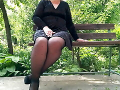 Naughty cougar in tights pissing in the park on a bench – rear view