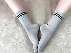 девушка в постели гладит свои ноги в серых хлопчатобумажных носках