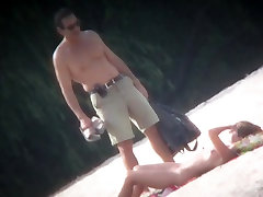 间谍凸轮射击中的一个热的裸体女人采取在海滩上