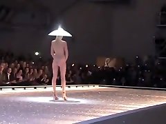 Seductive fashion heels pegging in a weird hat walks down the catwalk in the nude