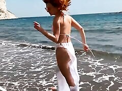 Sexy red-haired girl enjoys a walk by the sea