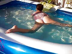 Elegant and flexible babe, swimming underwater in the outdoor swimming pool. SWIMMINGSUITE