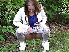 Amateur ebony head pees right on the green grass in the public park
